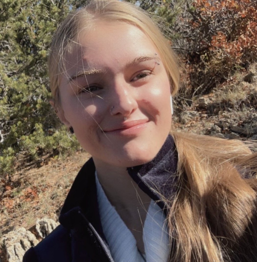 Selfie of Kadence Presser in front of pine trees.